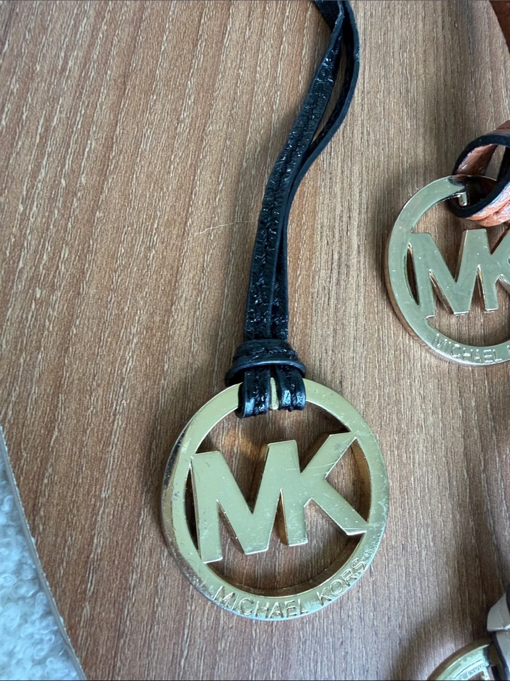 Set of four Michael Kors MK logo handbag charms featuring large round gold-tone